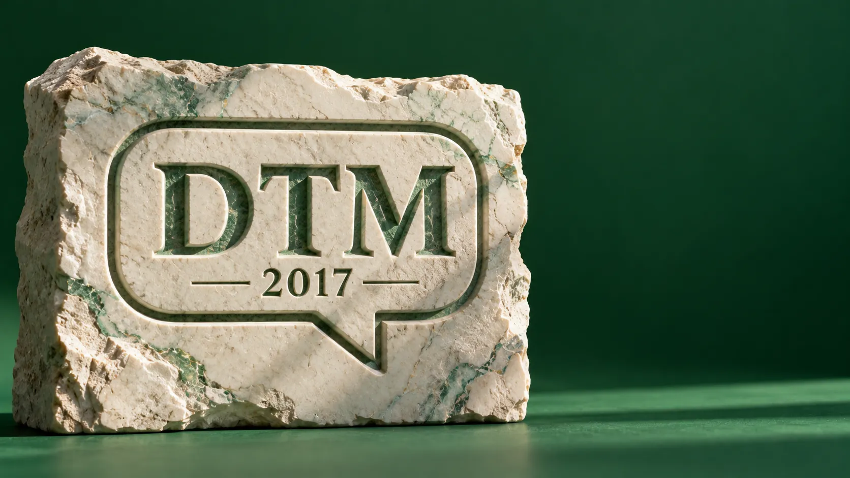 Carved marble relief of a speech bubble with the letters DTM above the year 2017