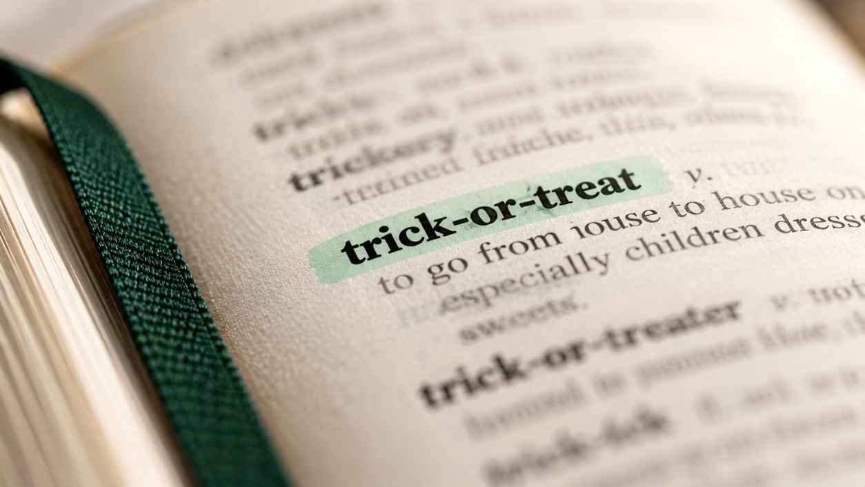 Macro shot of a printed dictionary page with the word trick-or-treat marked by a mint highlighter stripe